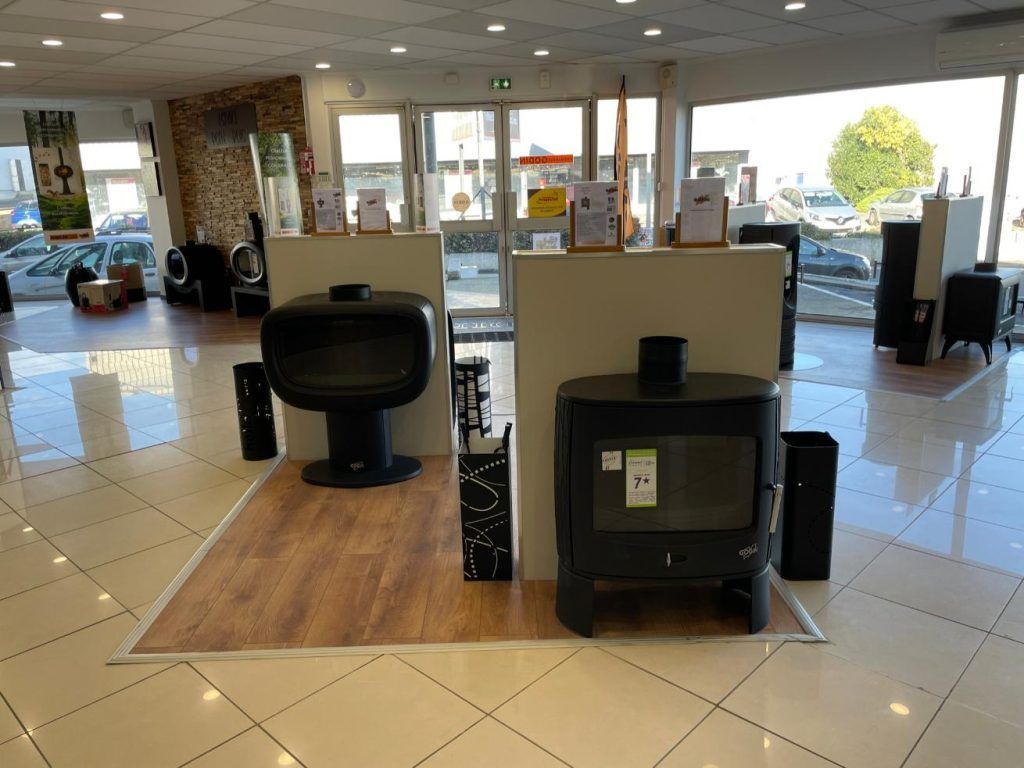 Intérieur d'un magasin présentant des poêles à bois, un parquet clair et un éclairage vif.