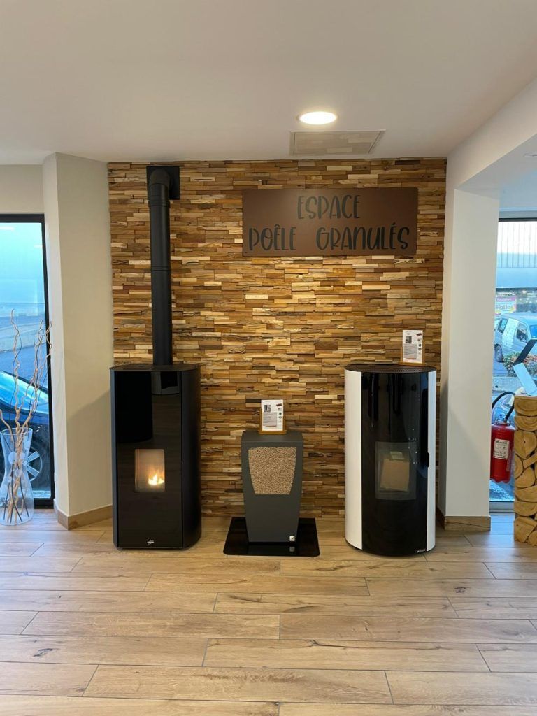 Trois poêles modernes sont exposés contre un mur lambrissé dans une salle d'exposition.