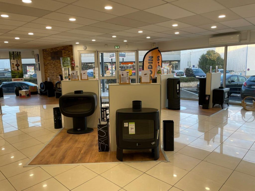 Salle d'exposition avec plusieurs poêles en démonstration, sol carrelé, éclairage vif.