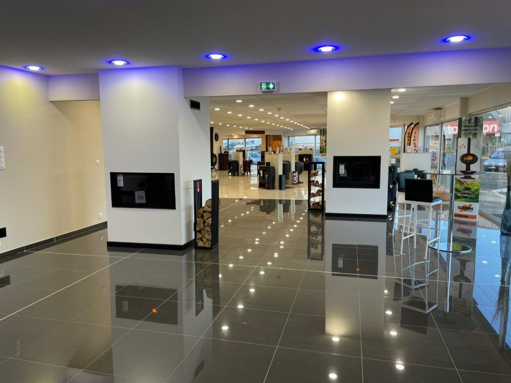 Intérieur de showroom moderne avec cheminées, sol brillant et éclairage vif.