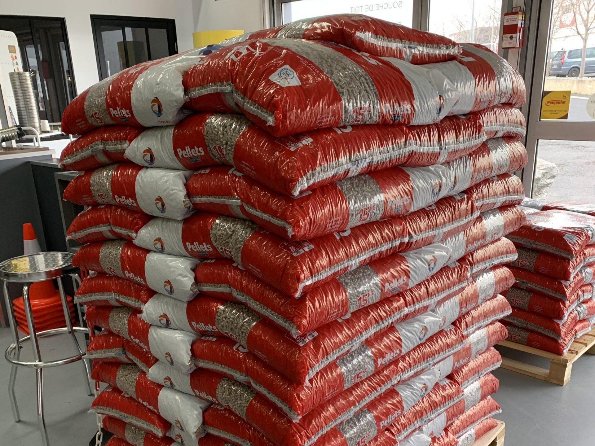 Pile de sacs de granulés à rayures rouges et blanches à l'intérieur d'un magasin.