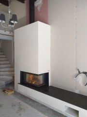 Cheminée moderne blanche avec foyer noir et feu incandescent, encastrée dans un mur.