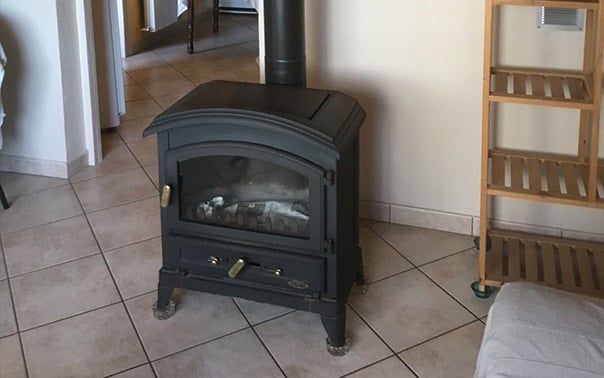 Poêle avec conduit dans une pièce au sol carrelé.