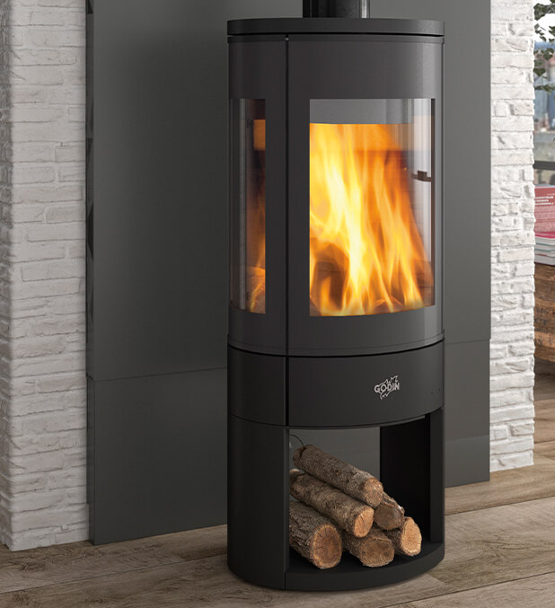 Intérieur d'une salle d'exposition présentant divers foyers et poêles, avec de grandes fenêtres donnant sur un parking.