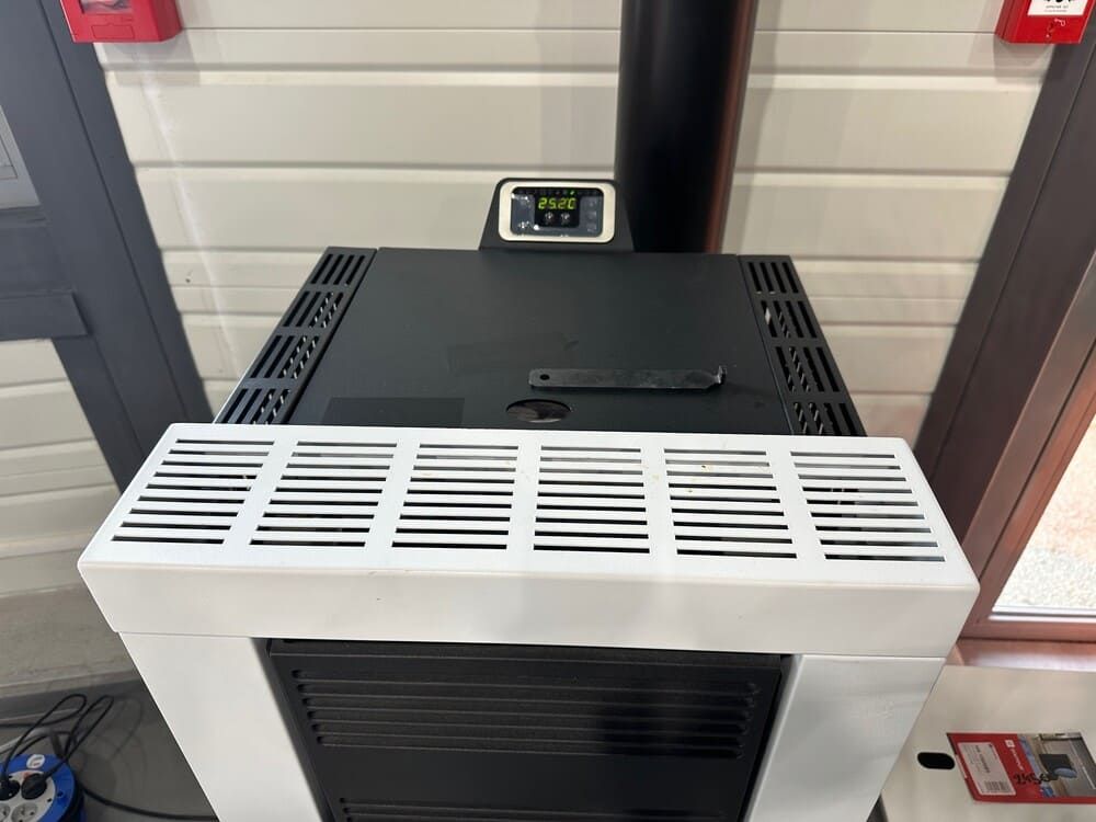 Un poêle à granulés blanc et noir avec affichage numérique et conduit de cheminée noir.