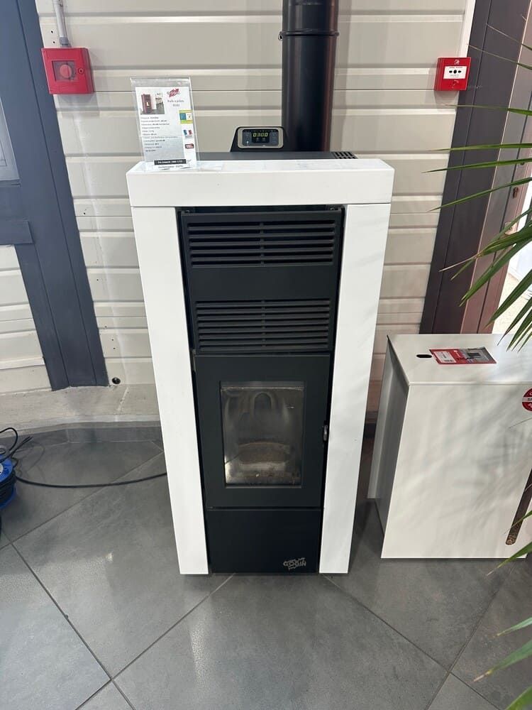 Poêle à granulés blanc et noir avec conduit d'évacuation, cheminée et panneau de commande.