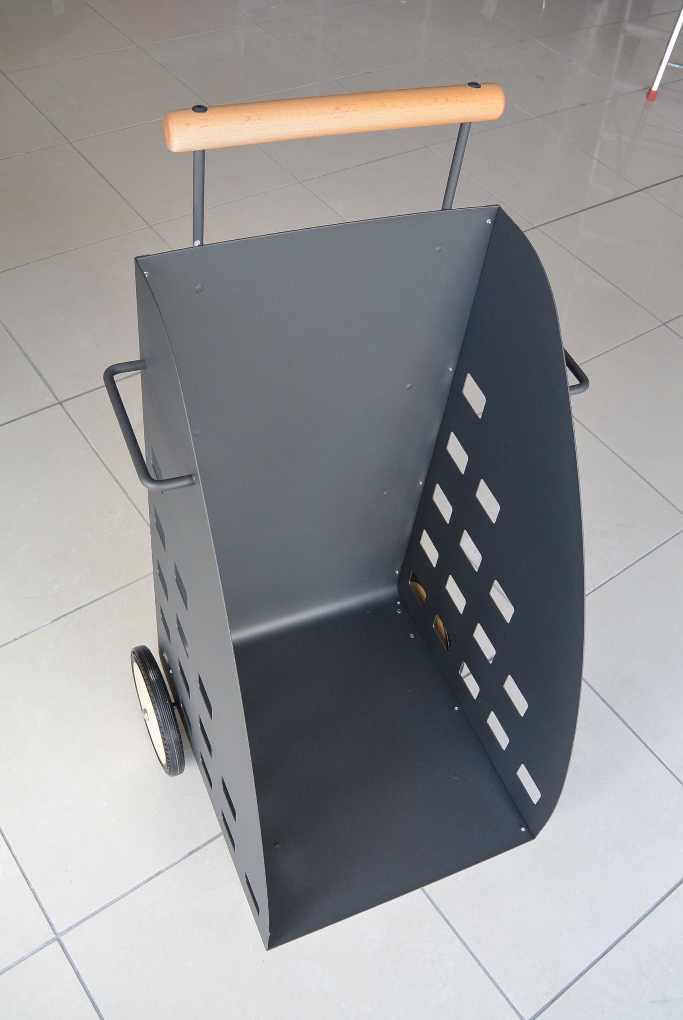 Caddie de bûches en métal noir avec poignée en bois et roues.