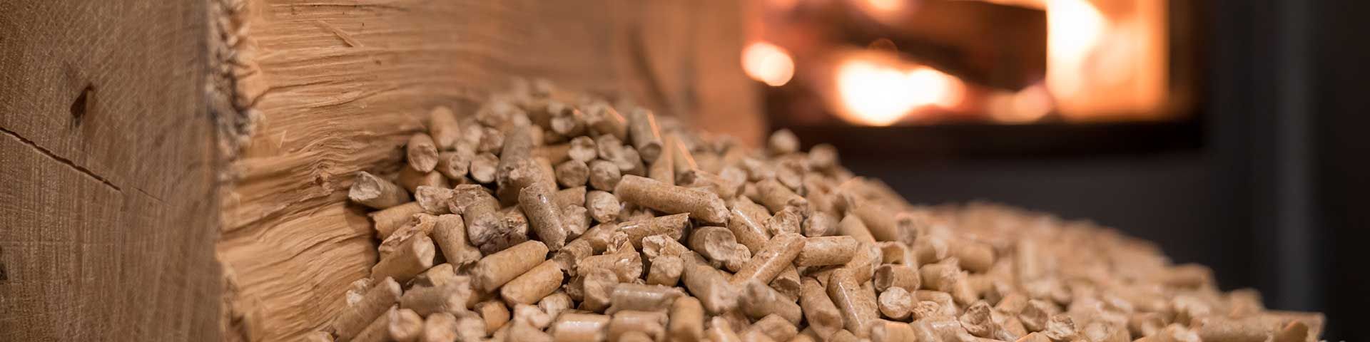 Un tas de granulés de bois devant une cheminée avec des flammes.