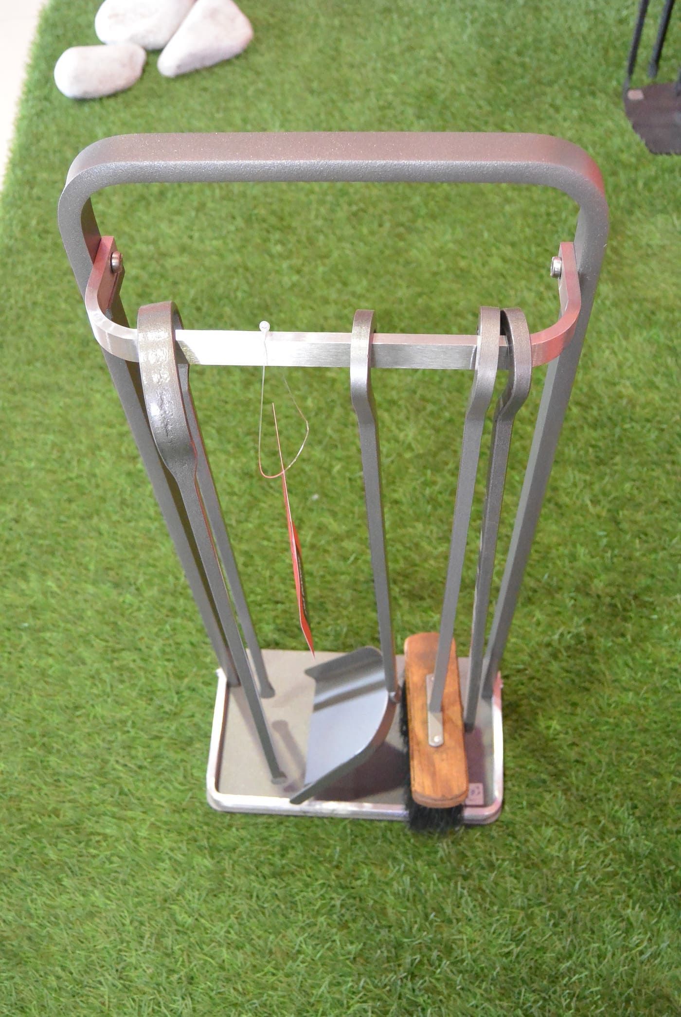 Ensemble d'outils de cheminée sur fond vert. Comprend une pelle, un tisonnier et un balai.