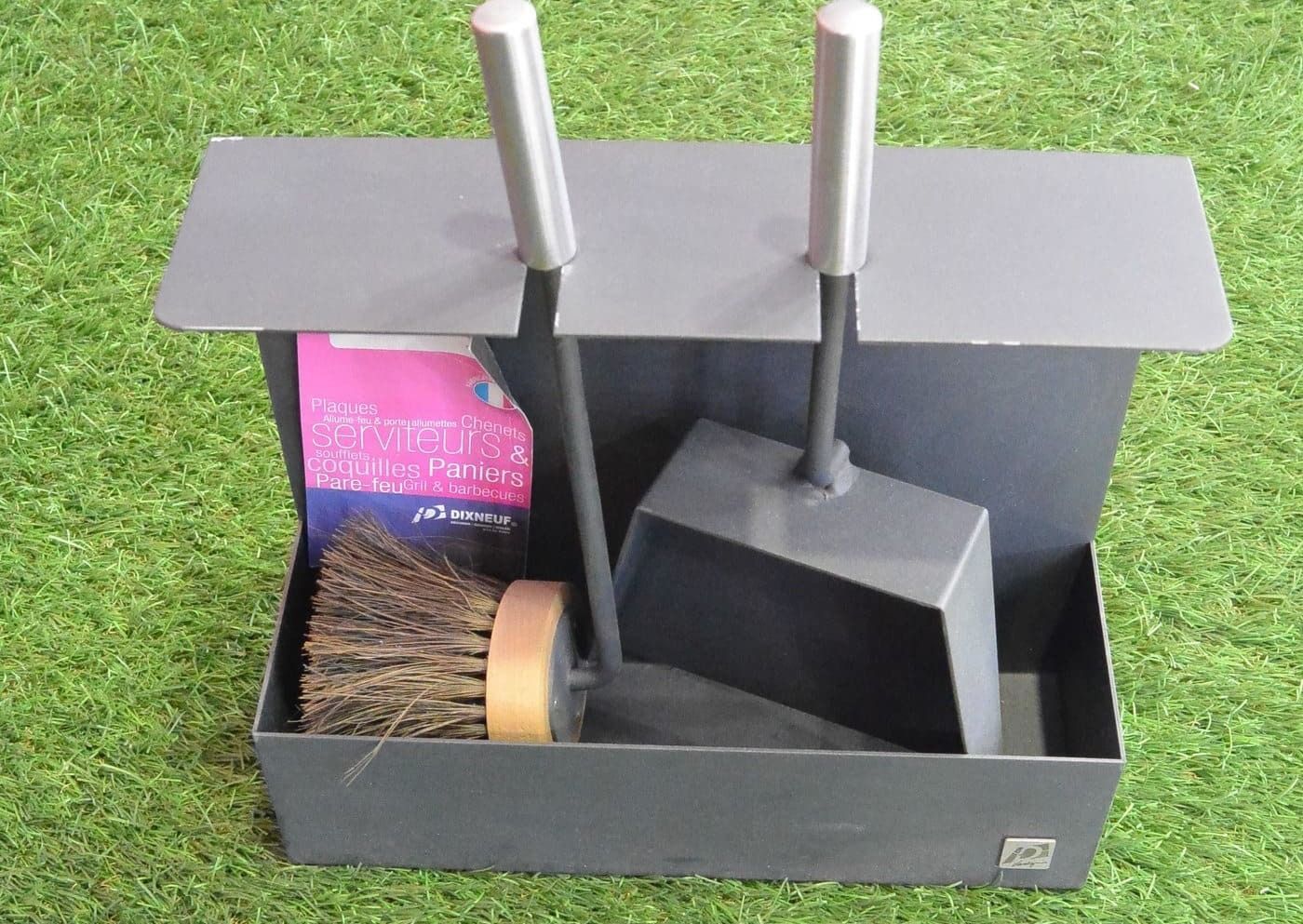 Ensemble d'accessoires de cheminée en métal gris sur gazon artificiel vert.