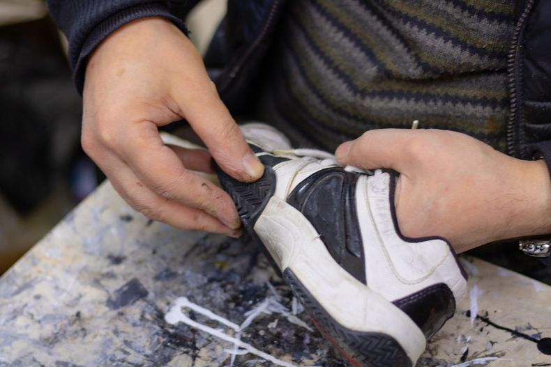 Una persona está arreglando un zapato en una mesa.