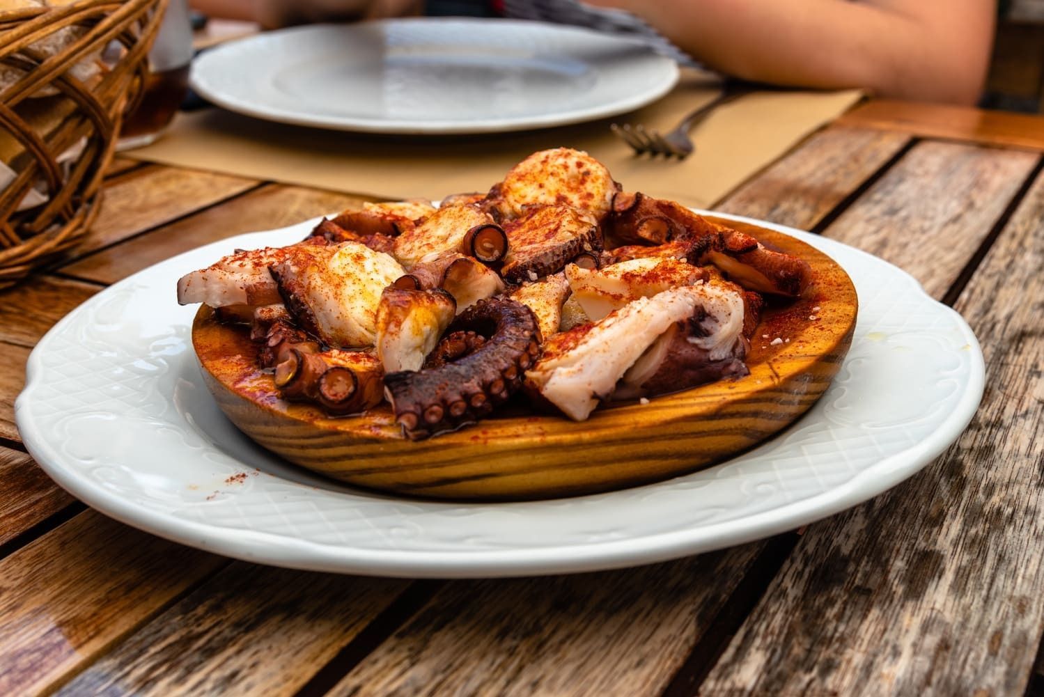 Un plato de pulpo en un plato de madera sobre una mesa de madera.