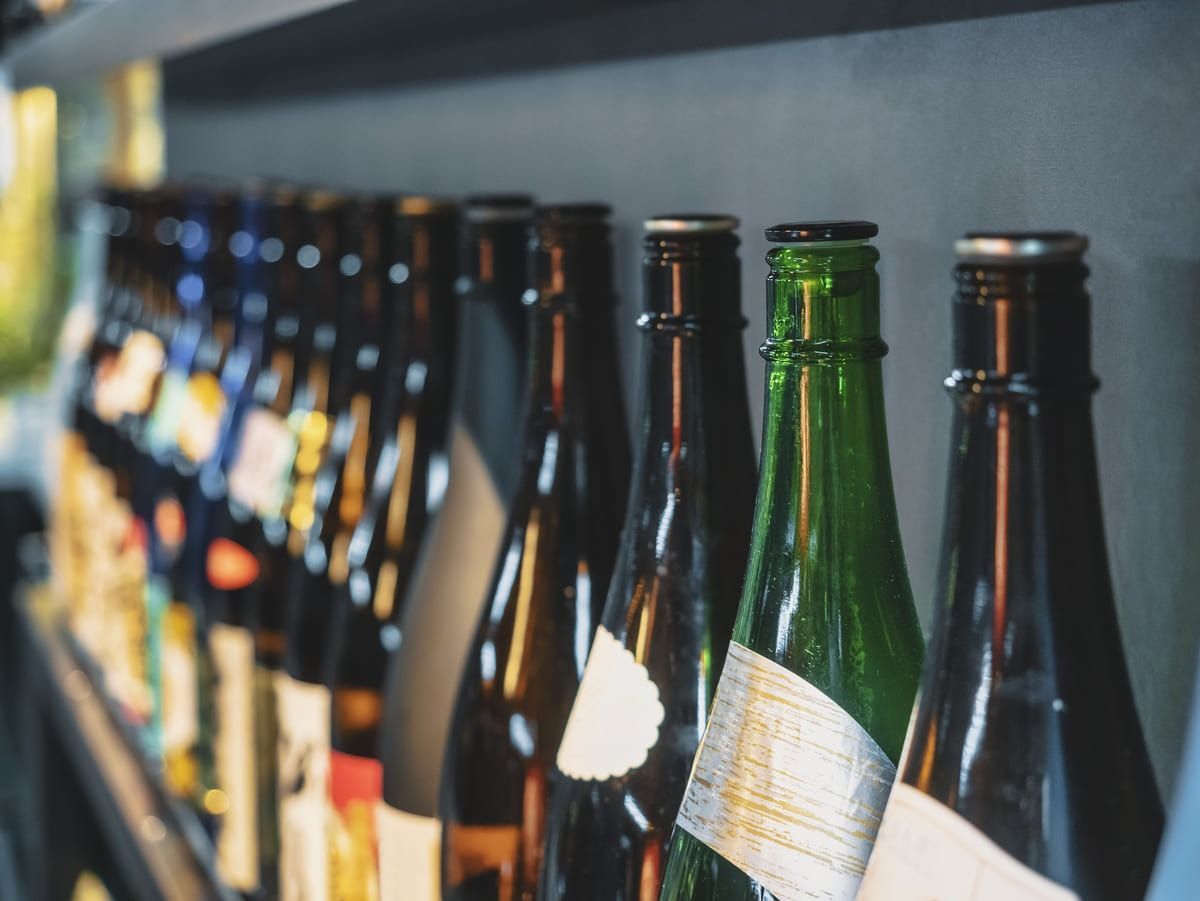 Una fila de botellas de vino están alineadas en un estante.