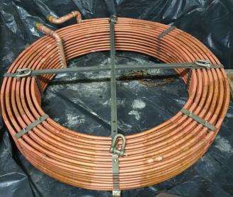 Una bobina de tubos de cobre se encuentra encima de una bolsa de plástico negra.