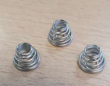 Tres resortes de metal están sobre una mesa de madera.