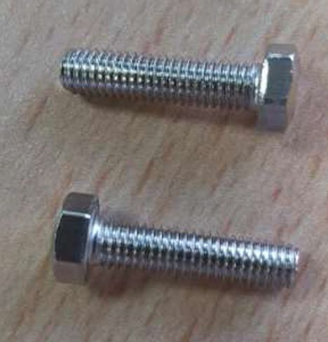 Dos tornillos de acero inoxidable están sobre una mesa de madera.