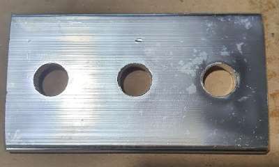 Una placa de metal con tres agujeros está sobre una mesa.