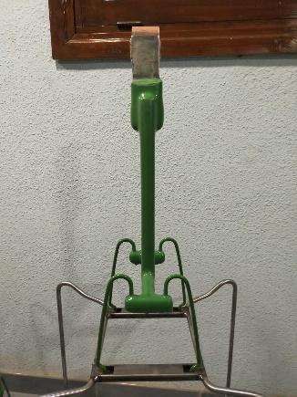 Un porta trapeador verde está colgado en una pared al lado de una ventana.