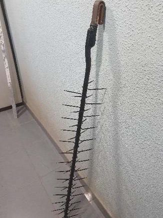 Un palo muy largo con puntas afiladas está colgado en una pared.