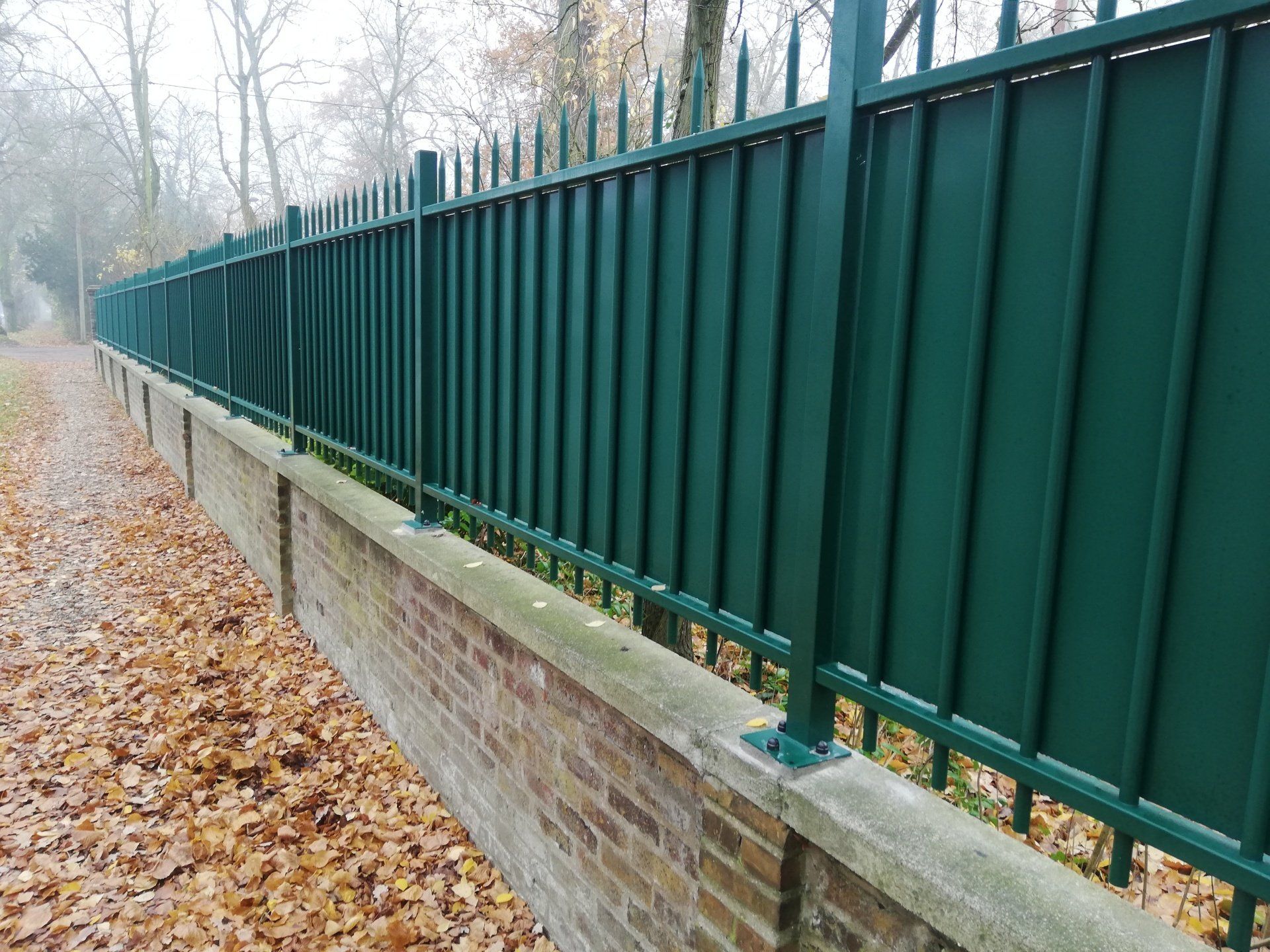 Clôtures verte en fer forgé sur muret en brique