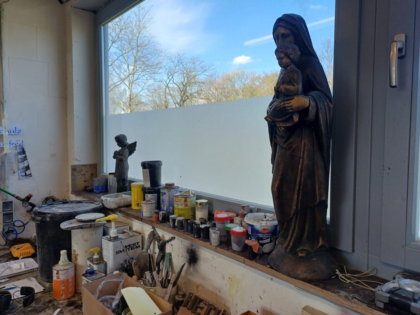 Auf einem Fensterbrett sitzt die Statue einer Frau, die ein Baby hält.