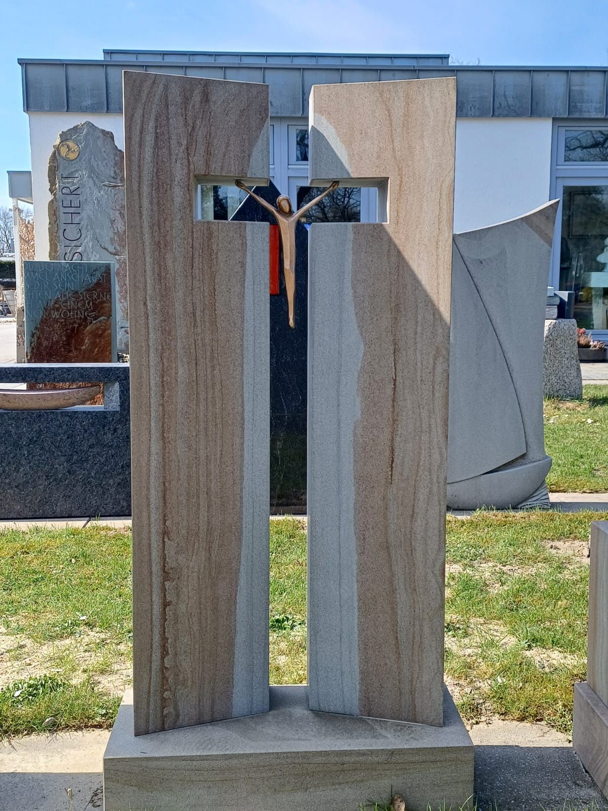 Vor einem Gebäude steht eine Kreuzstatue mit Jesus darauf.