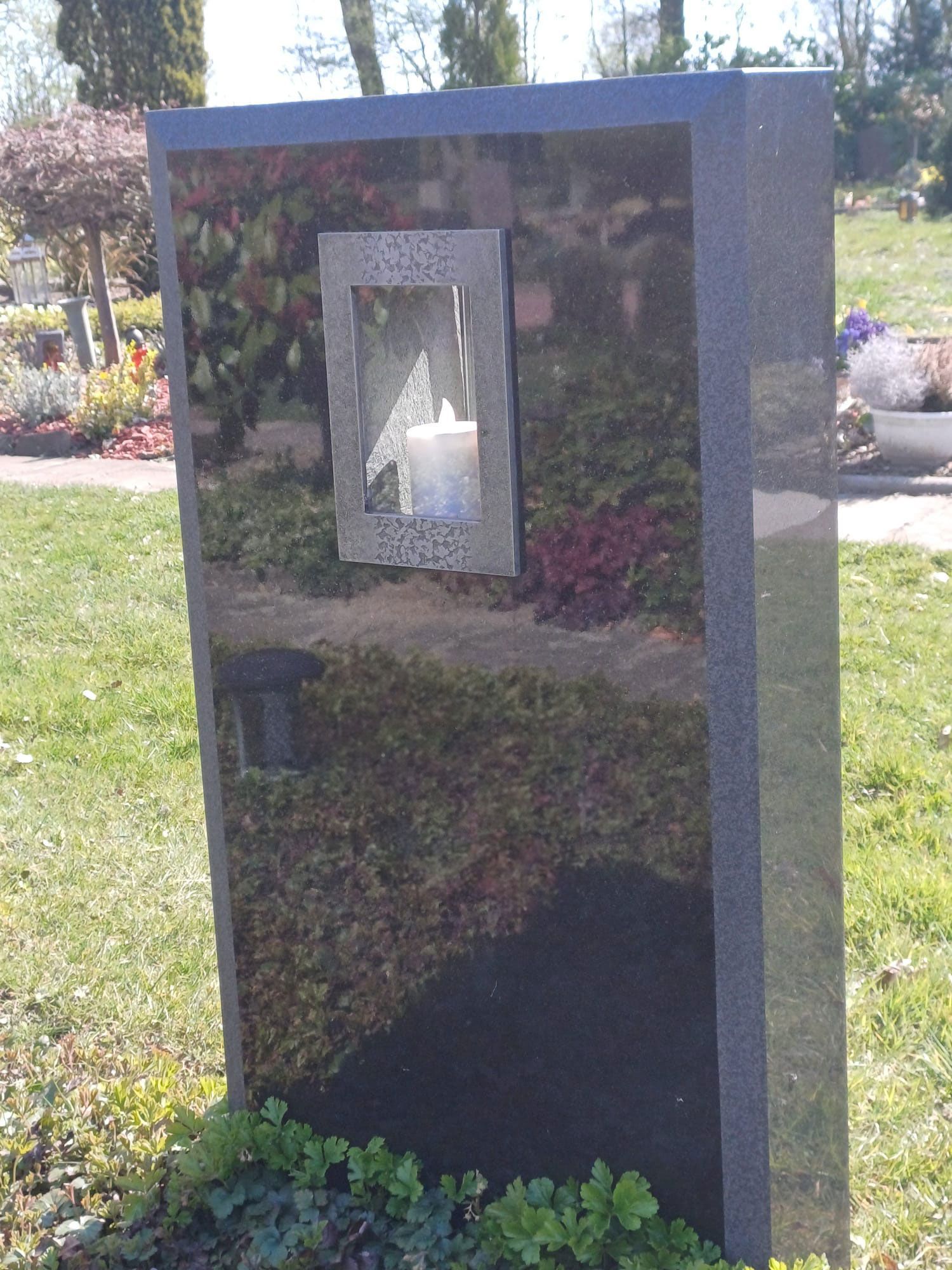 ein Grabstein mit eingelassener Kerze 