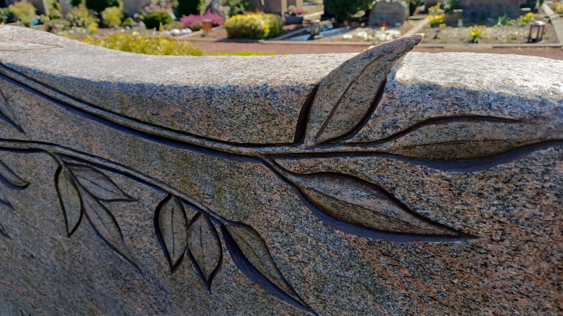 Eine Nahaufnahme eines Grabsteins mit eingravierten Blättern