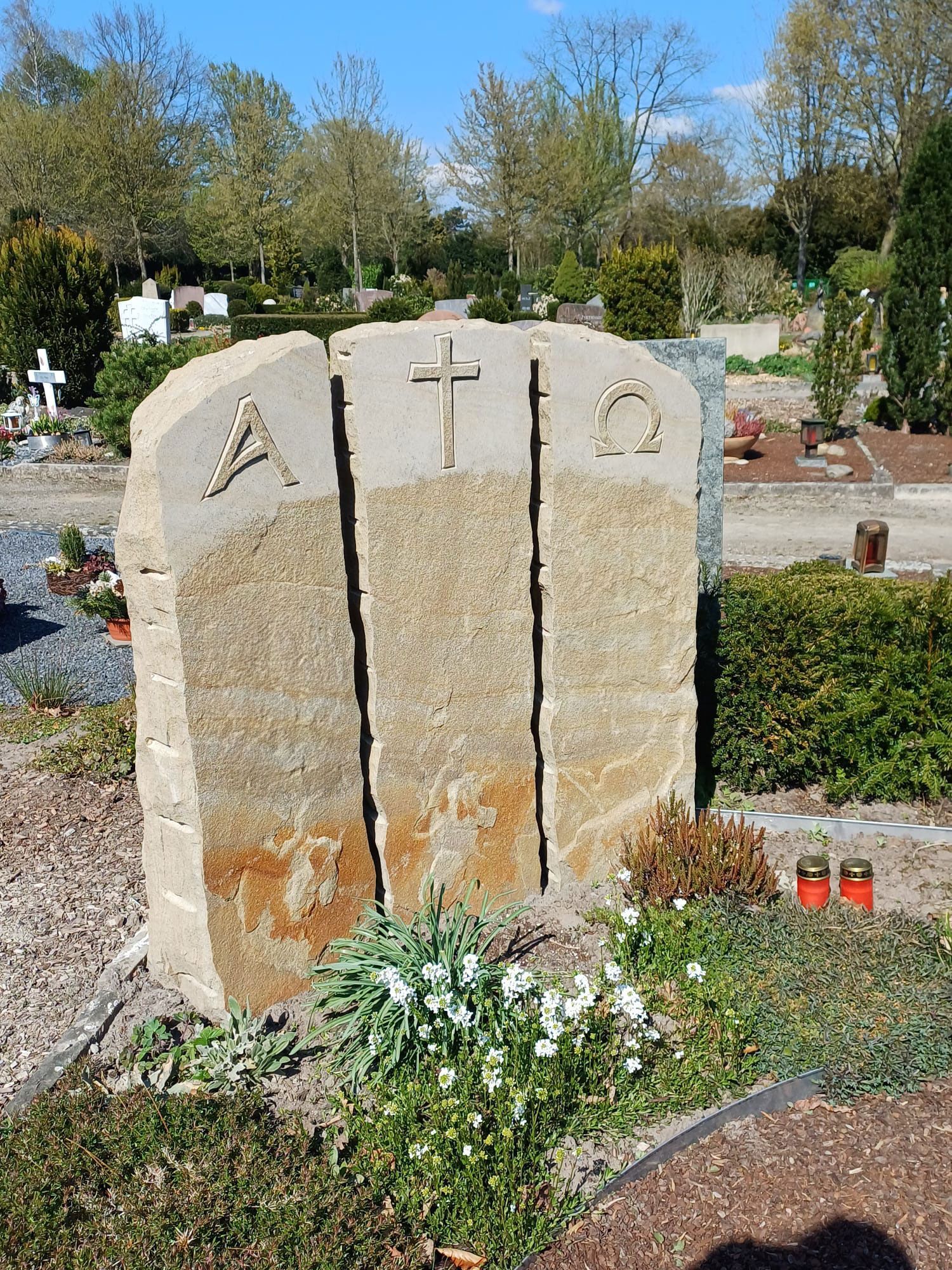 Ein Grabstein auf einem Friedhof, in den ein Kreuz eingemeißelt ist.