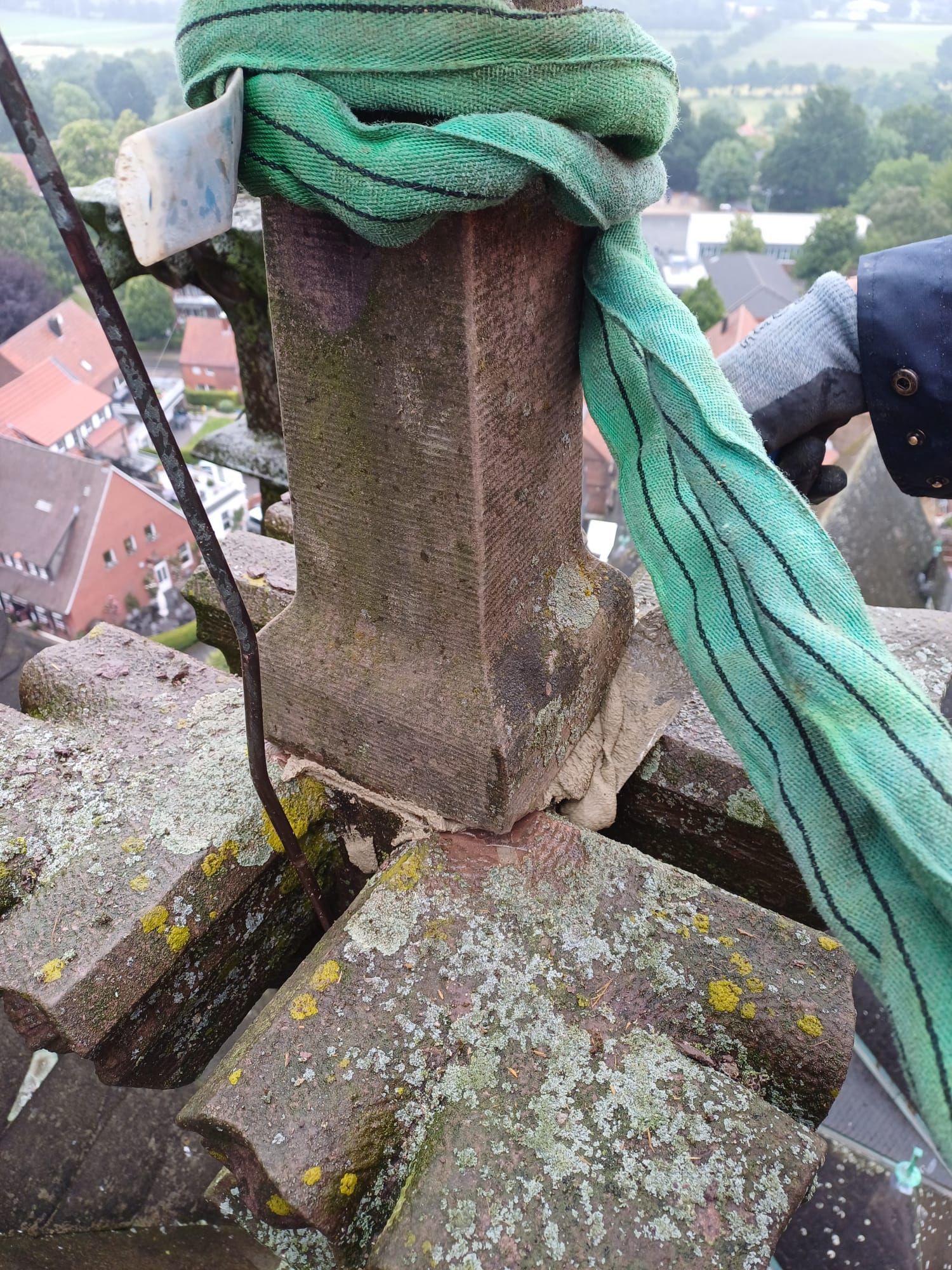 Eine Person hält ein grünes Seil um eine Steinstruktur.