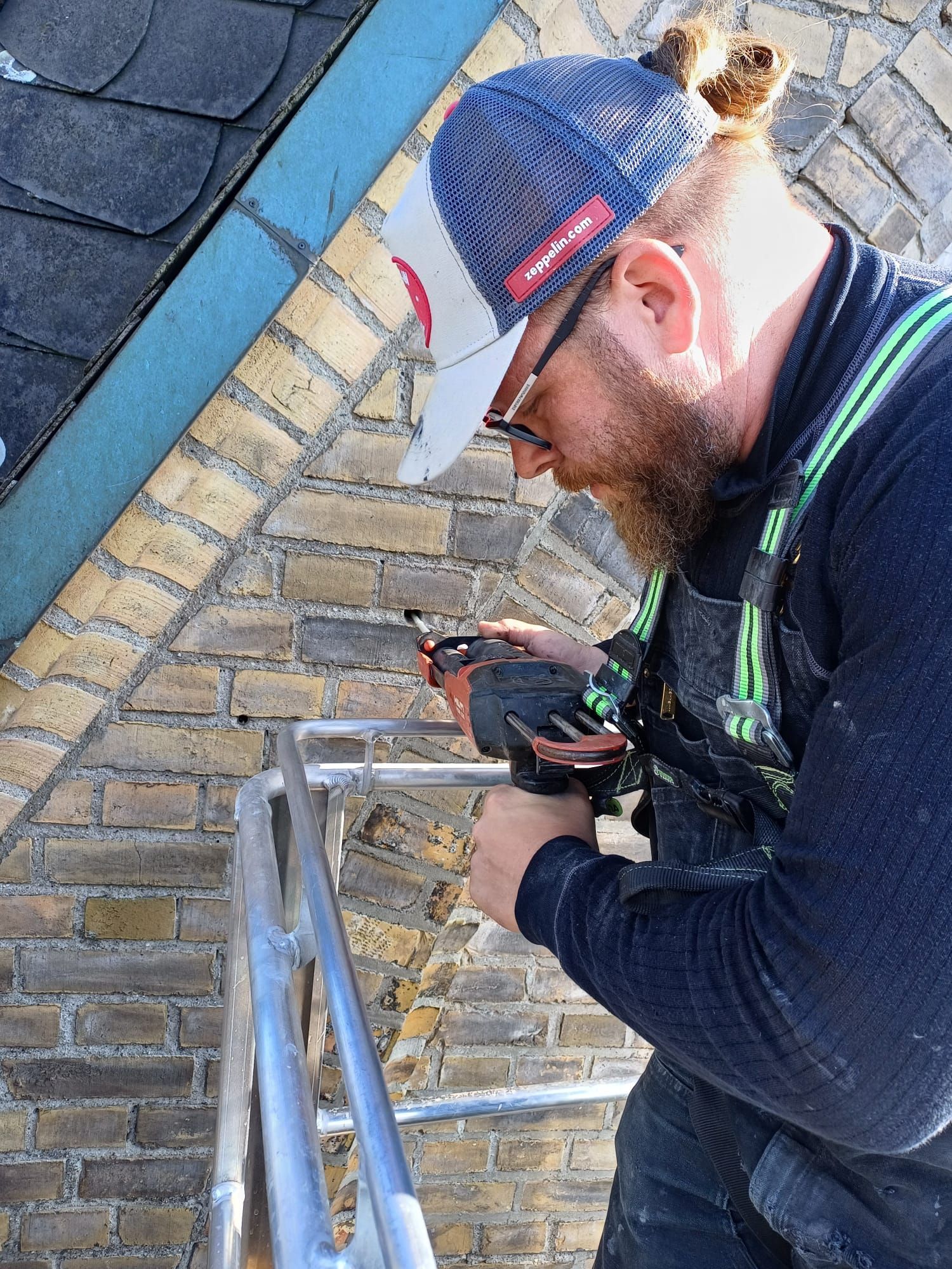 Ein Mann steht auf einer Leiter und schaut auf ein Messgerät.