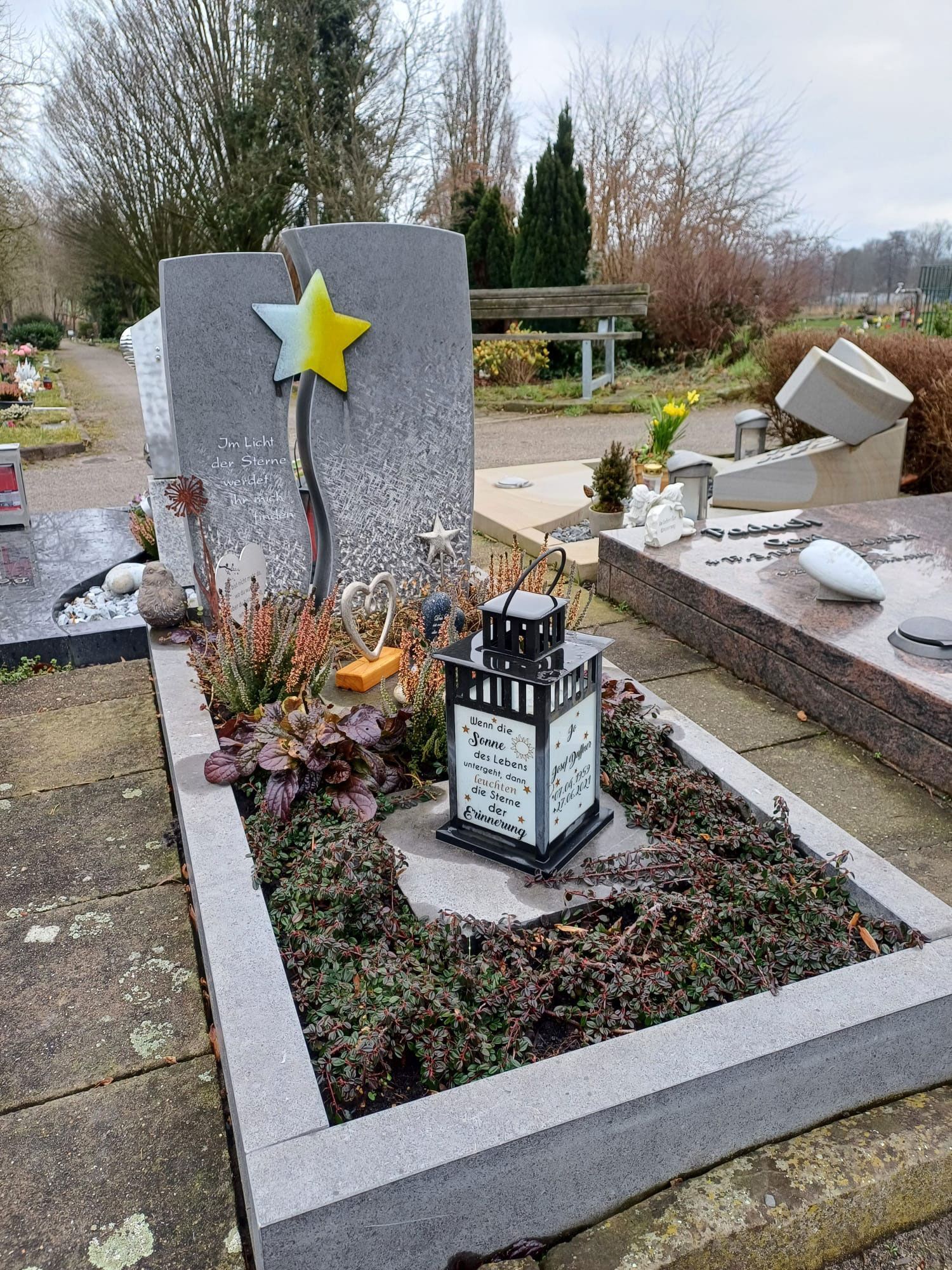 Ein Grab mit einer Laterne und einem Stern darauf auf einem Friedhof.