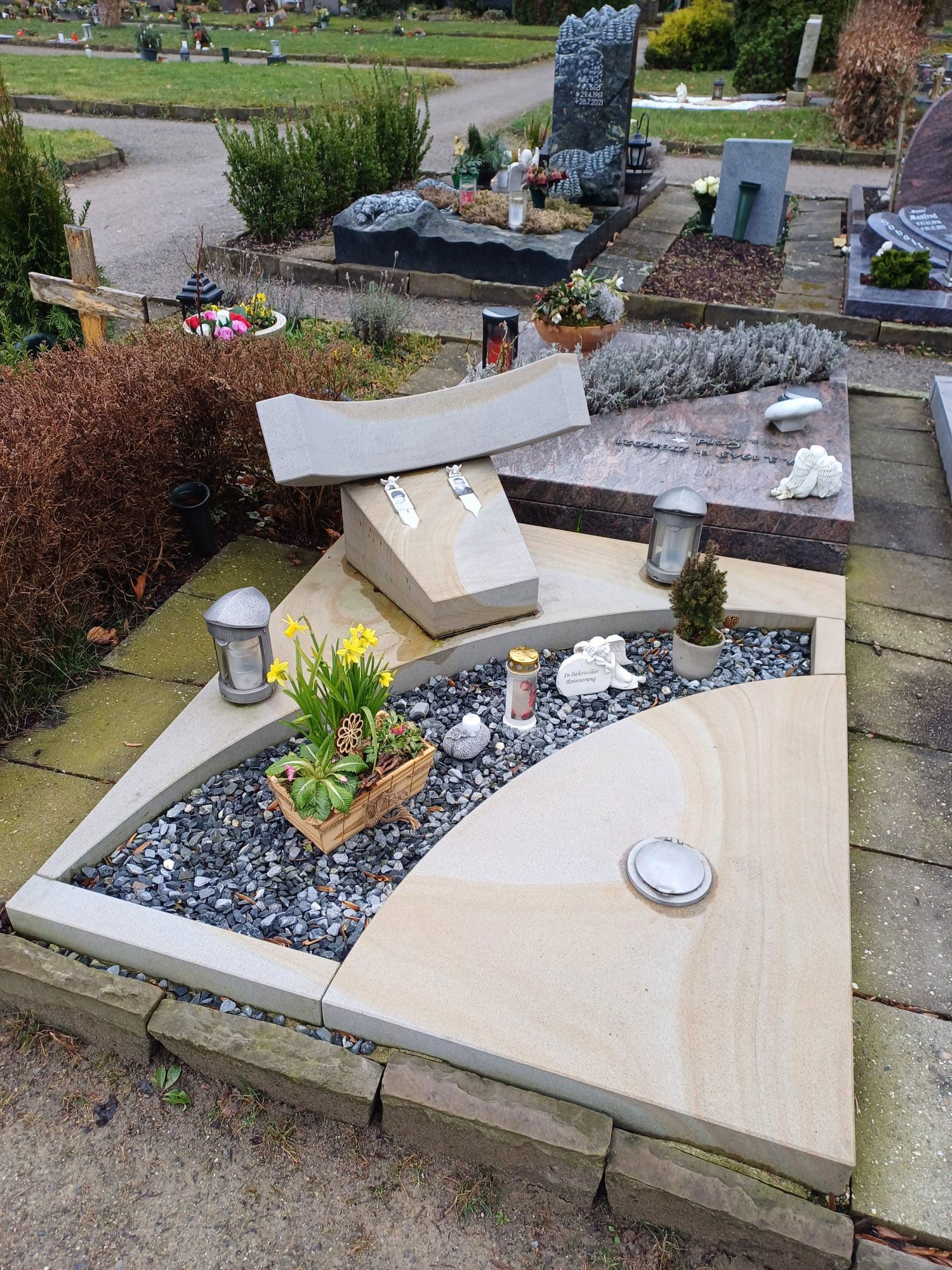 Ein Grab auf einem Friedhof mit Blumen und Kerzen darauf.