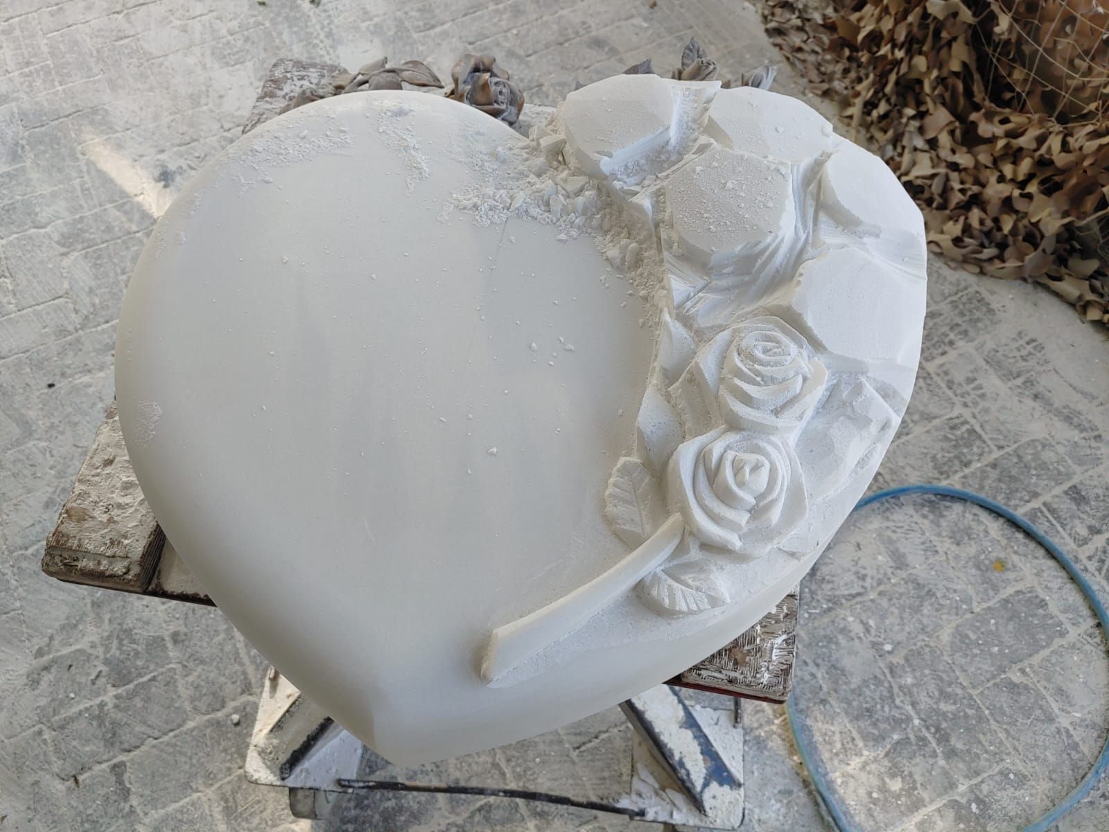 Auf einem Tisch liegt ein weißes Herz mit eingeschnitzten Rosen.