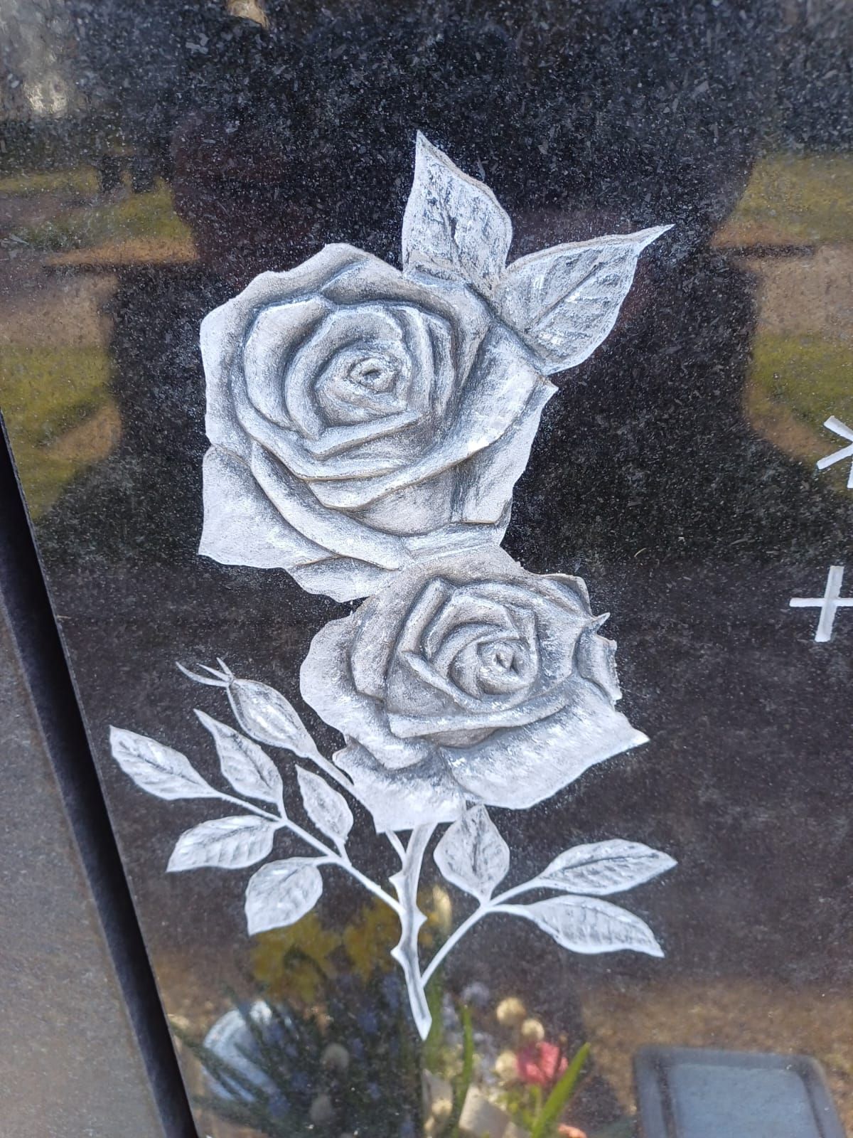 Ein Grabstein mit zwei weißen Rosen darauf