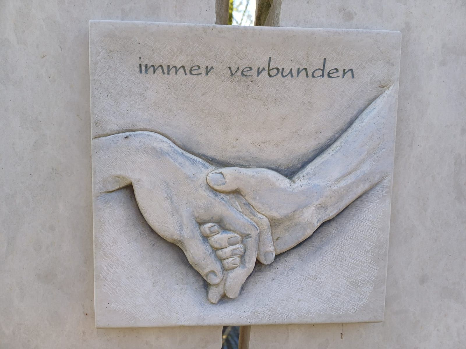 Eine Tafel mit zwei einander haltenden Händen und der Aufschrift „immer verbunden“