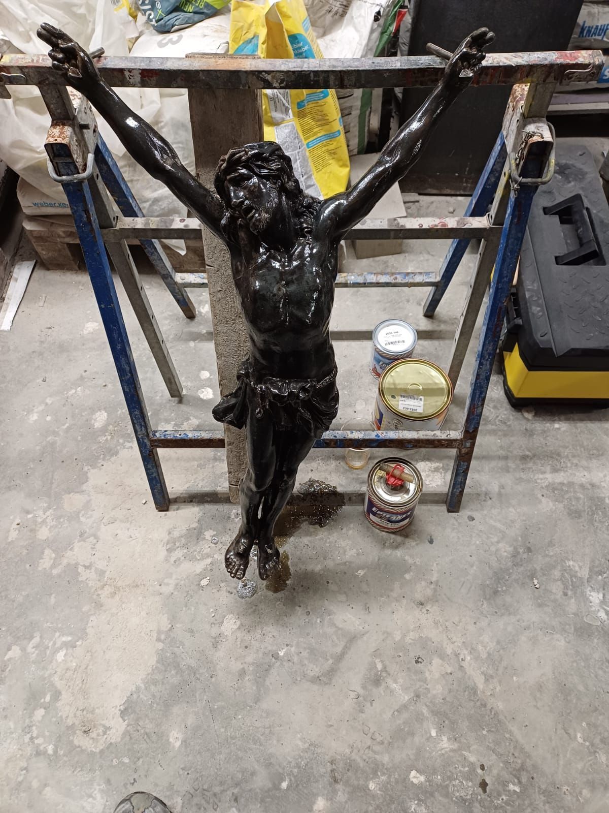 Eine Statue von Jesus am Kreuz ist mit schwarzer Farbe bedeckt.