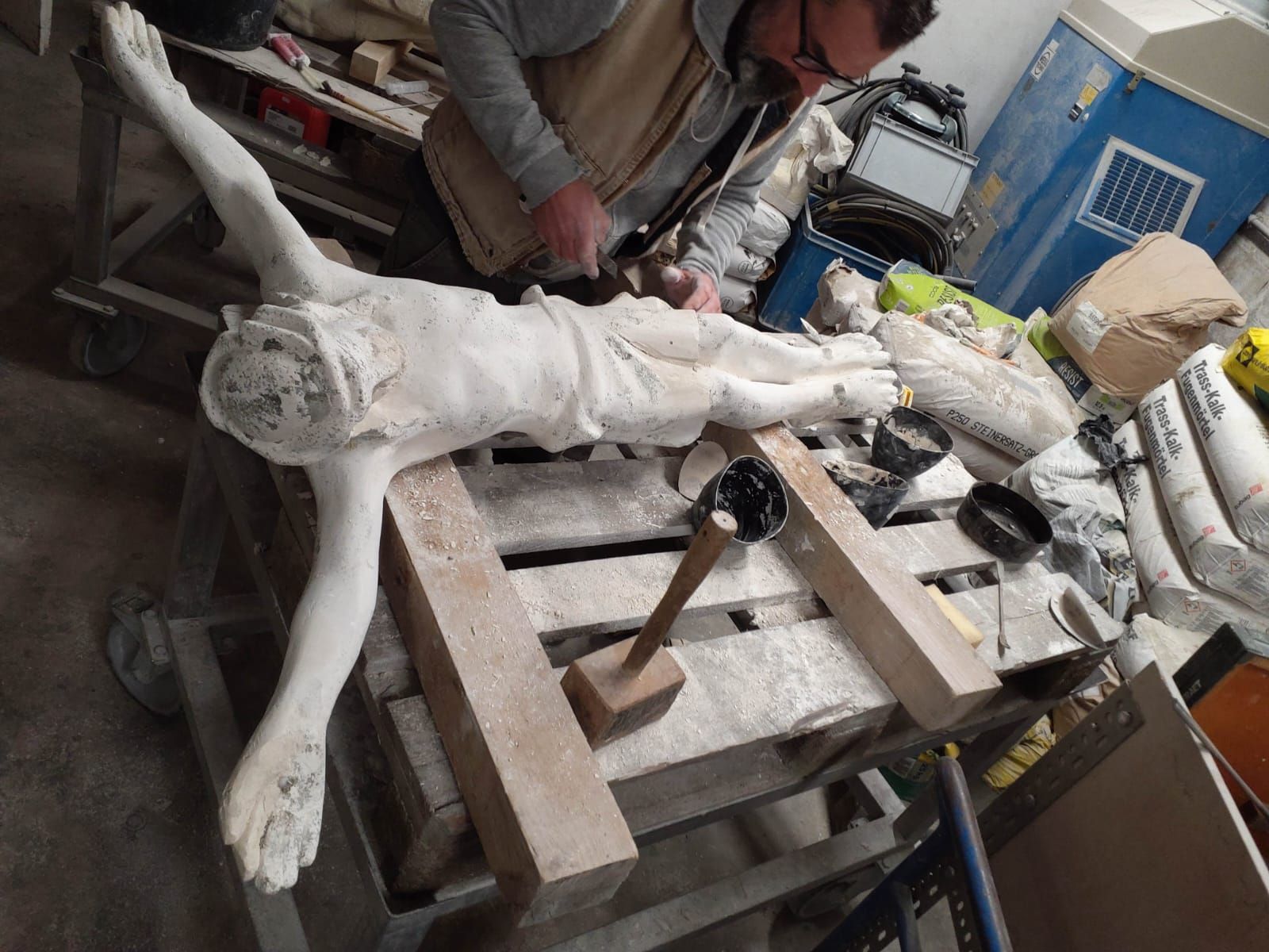Ein Mann arbeitet an einer Statue von Jesus am Kreuz