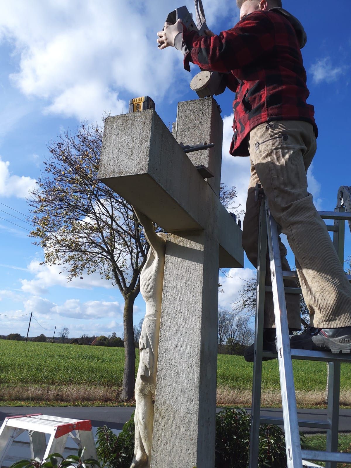 Ein Mann steht auf einer Leiter und arbeitet an einem Kreuz