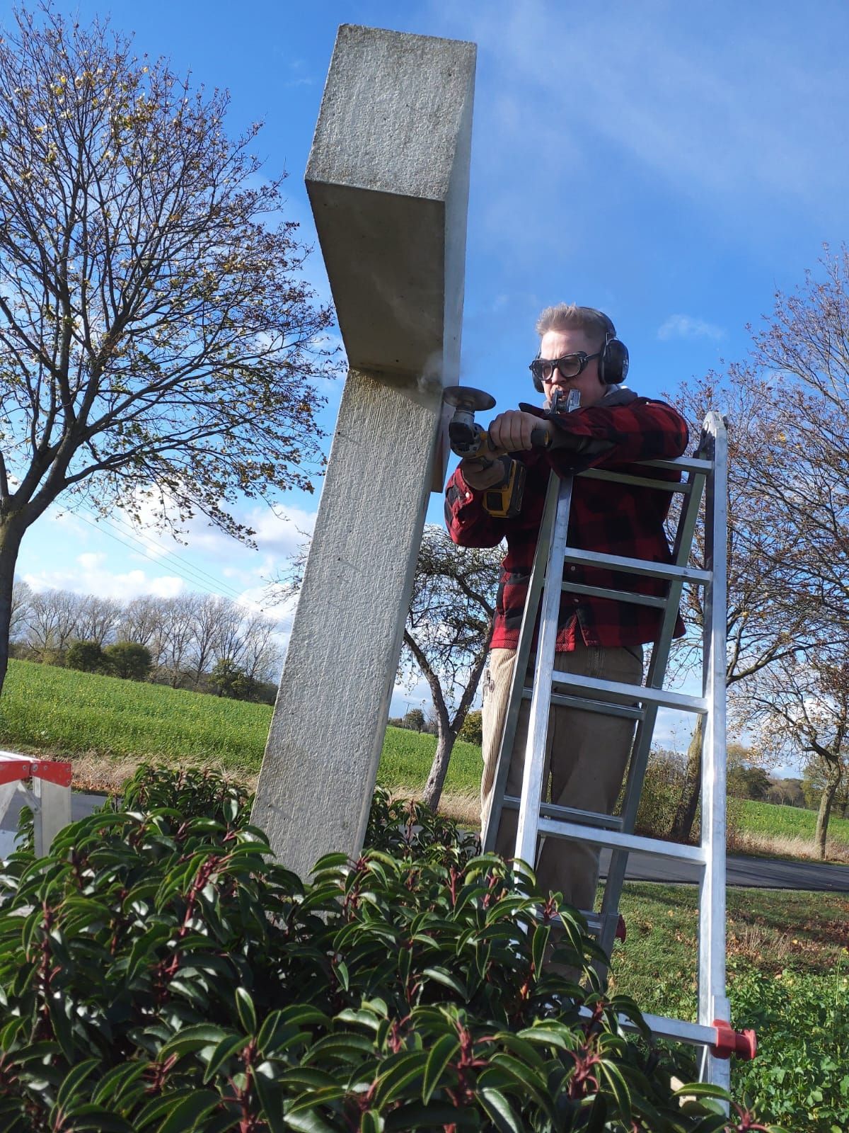 Ein Mann steht auf einer Leiter und arbeitet an einer Statue.