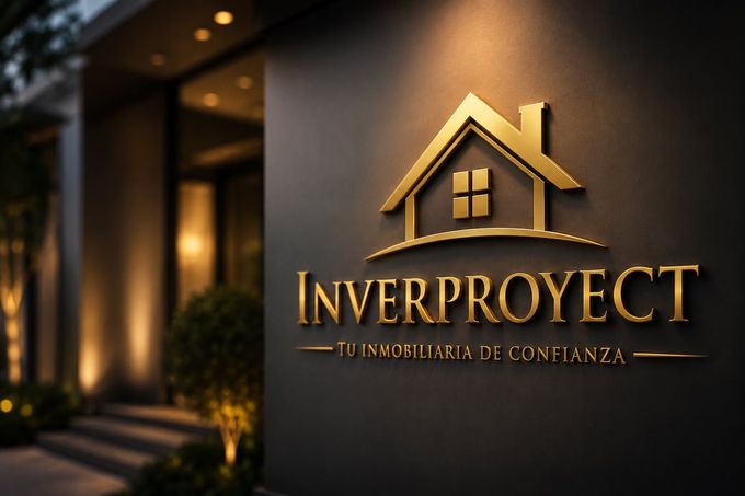Logotipo dorado de la inmobiliaria “Inverproyect” en la pared oscura de un edificio con iluminación cálida.