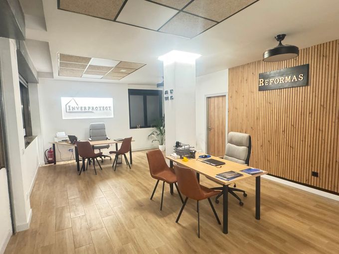 Sala de estar moderna con mesas, sillas y un gran letrero en la pared que dice