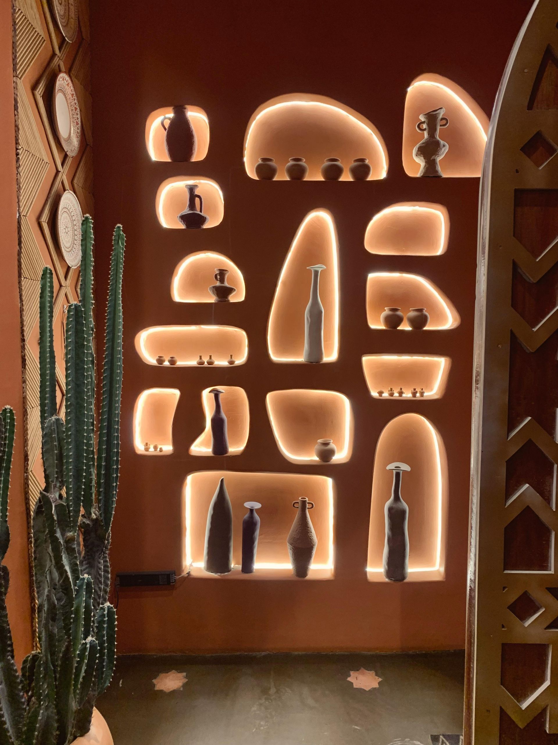 Estanterías empotradas de pladur con iluminación cálida que exhiben pequeñas piezas de cerámica