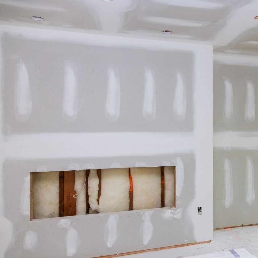 Interior de una habitación con paneles de yeso parcialmente instalados; se ve un recorte de chimenea que revela el aislamiento.
