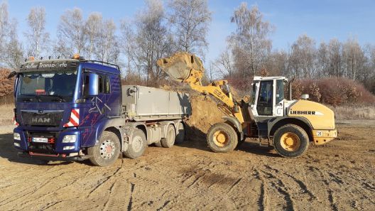 kleiner gelber Bagger neben einem kleinen Lkw mit Ladeanhänger