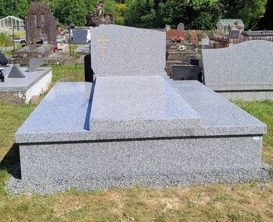 Monument funéraire en granit dans un cimetière, avec une pierre tombale polie.