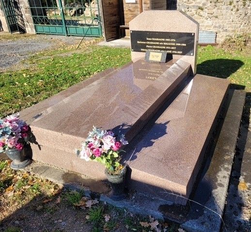 Tombe commémorative en pierre polie, pierre tombale gravée et deux pots de fleurs à côté d'un bâtiment