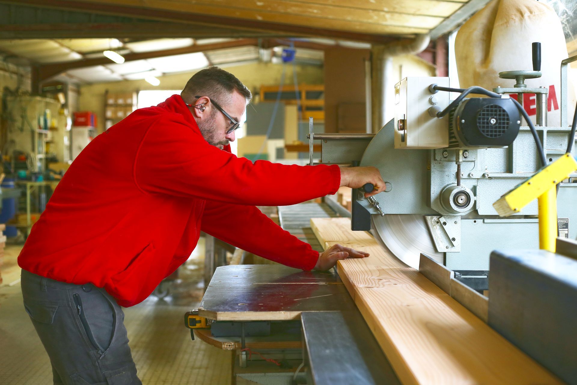 Une personne en train d'utiliser une machine à découper une planche de bois