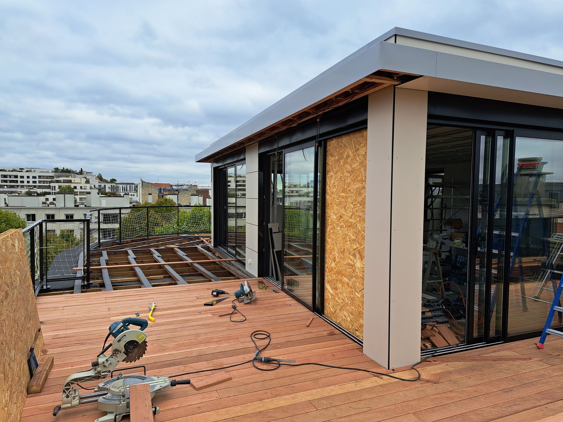 Terrasse en bois en train d'être placée autour d'une maison sur un toit plat