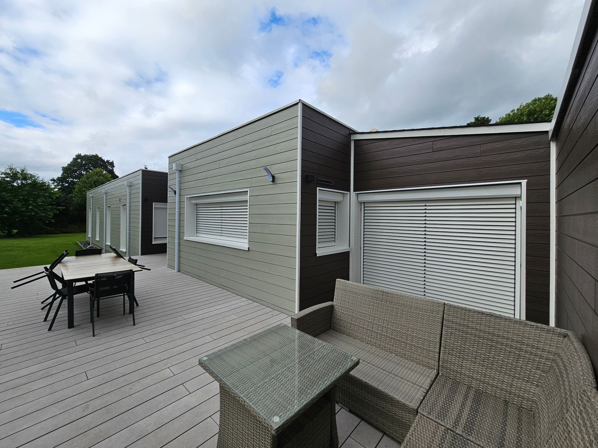 Sièges et tables sur la terrasse en bois d'une habitation